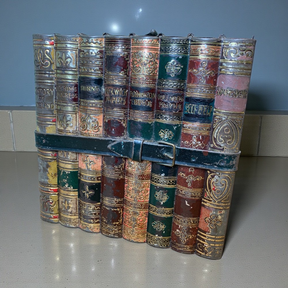 An Edwardian lithographed tinplate biscuit box designed to resemble a row of classic leather-bound books held together by a faux strap. View II
