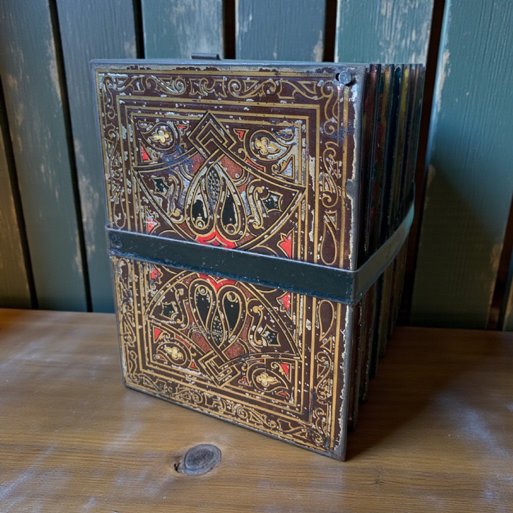 An Edwardian lithographed tinplate biscuit box designed to resemble a row of classic leather-bound books held together by a faux strap. View V