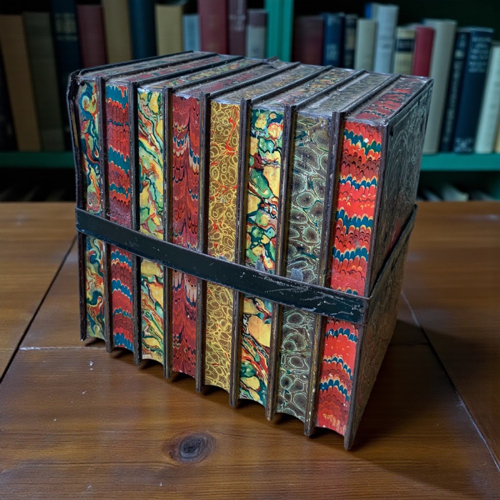 An Edwardian lithographed tinplate biscuit box designed to resemble a row of classic leather-bound books held together by a faux strap. View VI