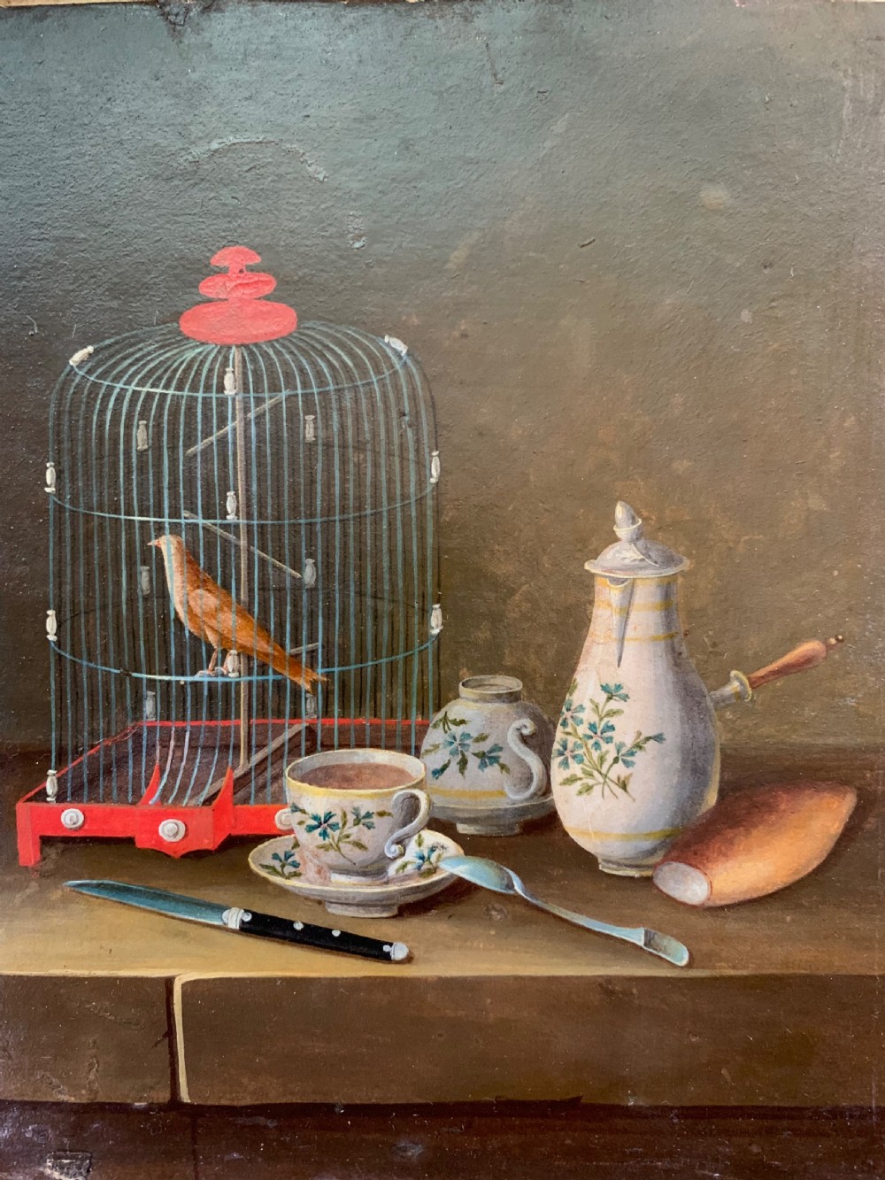 An early nineteenth-century framed French gouache still-life painting depicting a tabletop scene with a bird in a cage, a floral vase, porcelain teaware, and a book set within a carved giltwood frame. View IV