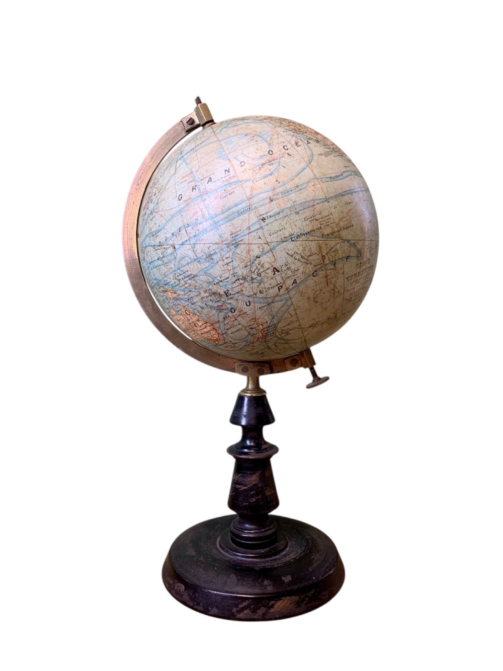 A vintage French terrestrial globe featuring cream paper map gores on a brass meridian half-ring and a turned dark wood pedestal base.