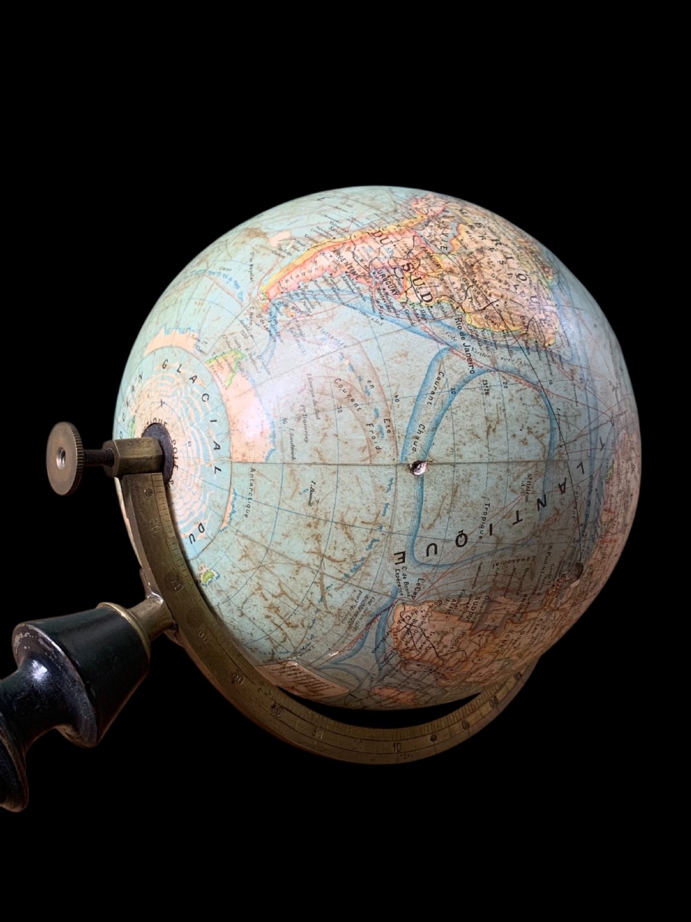 A vintage French terrestrial globe featuring cream paper map gores on a brass meridian half-ring and a turned dark wood pedestal base. View V