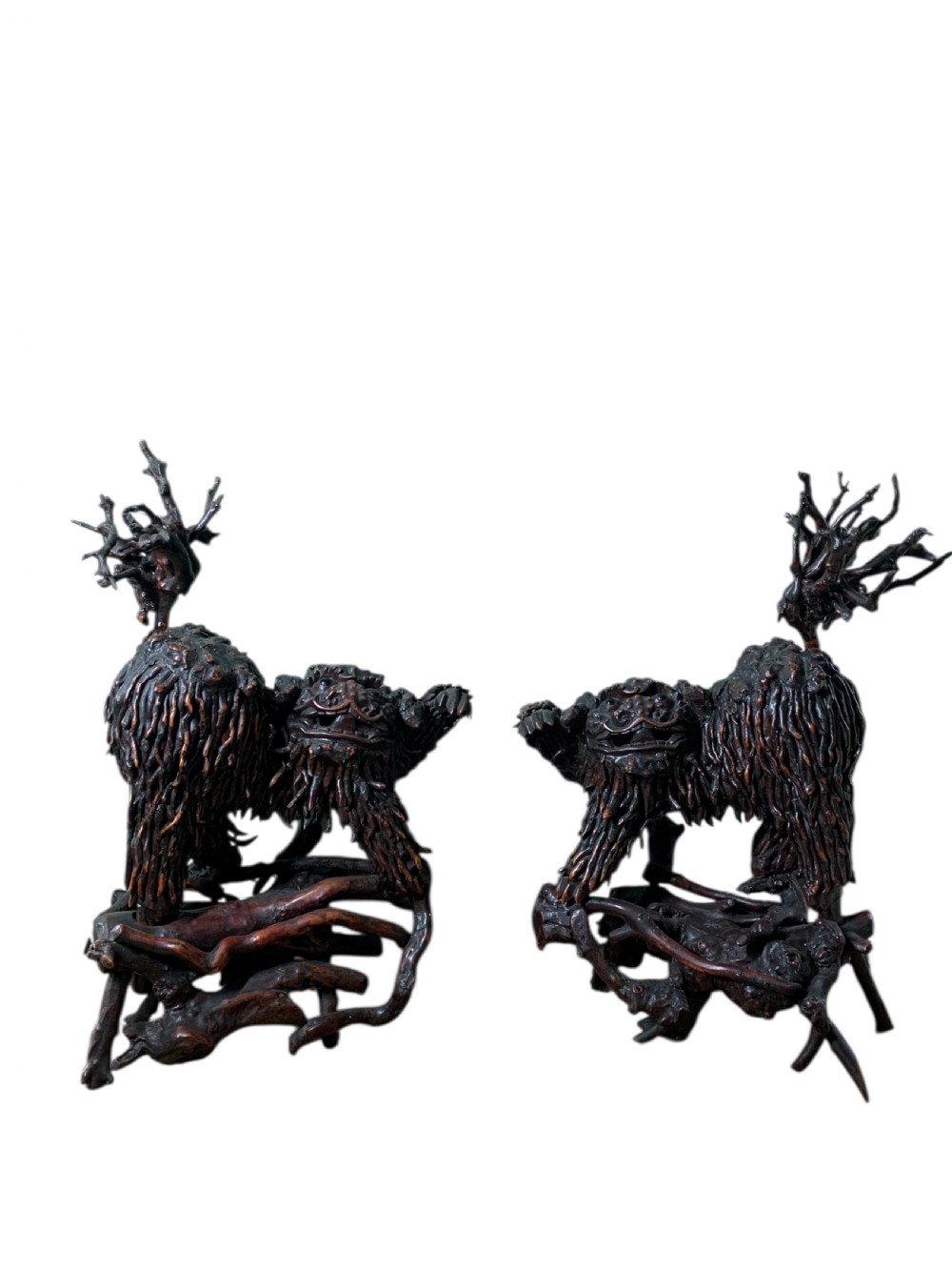 A pair of dark carved root wood Chinese guardian lion sculptures raised on organic natural root bases. View II
