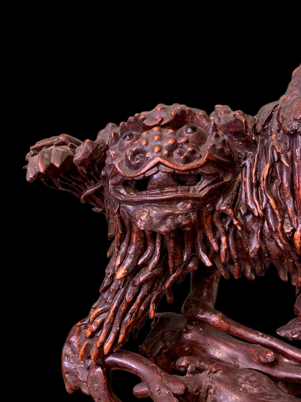 A pair of dark carved root wood Chinese guardian lion sculptures raised on organic natural root bases. View IX