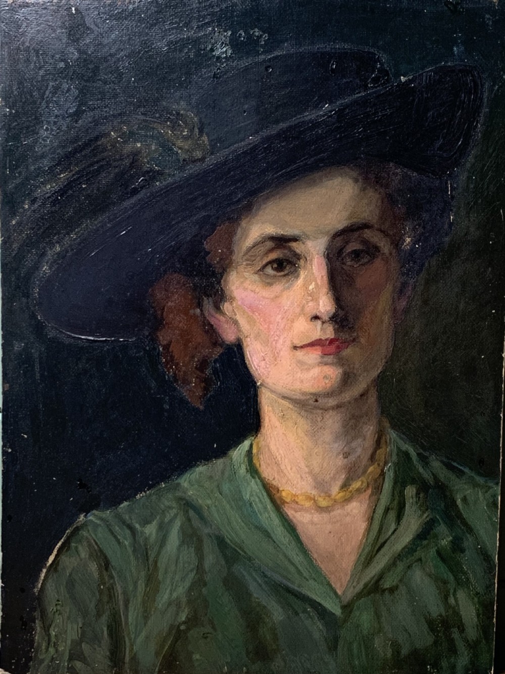 An oil painting on board depicting a woman wearing a wide-brimmed black hat with plumes, a green dress, and a yellow bead necklace against a dark background.