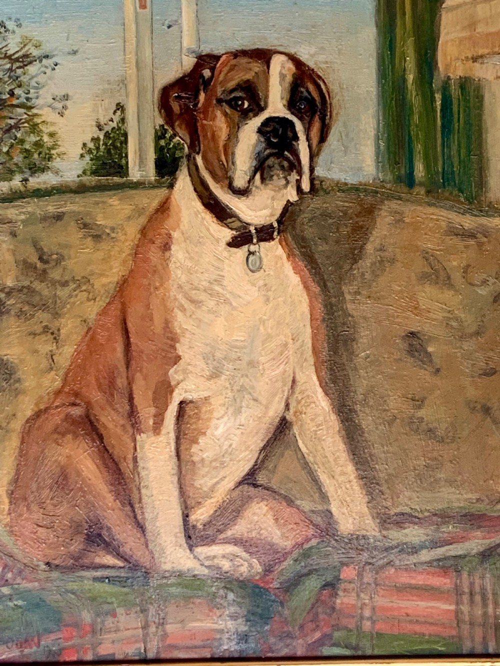 A framed oil painting on board depicting a brown and white Boxer dog seated indoors on a patterned sofa. View IV