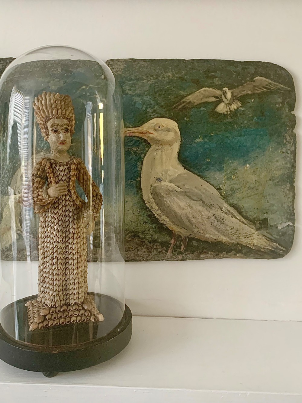 A standing figure of a woman sculpted from tiny arranged seashells on a circular dark wood base. View III