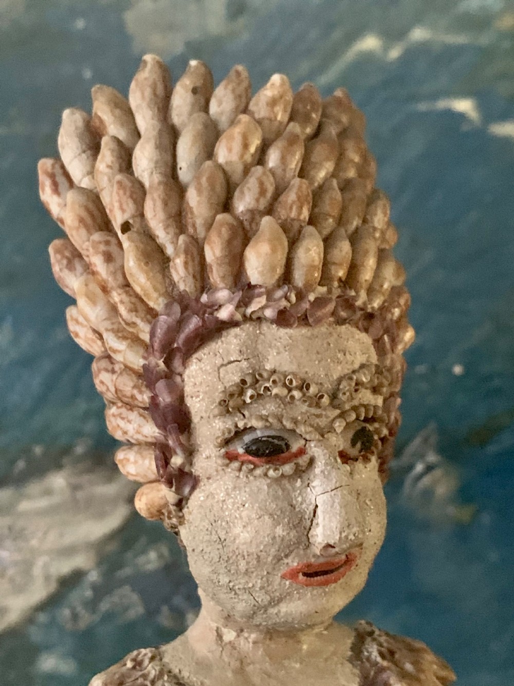 A standing figure of a woman sculpted from tiny arranged seashells on a circular dark wood base. View VIII