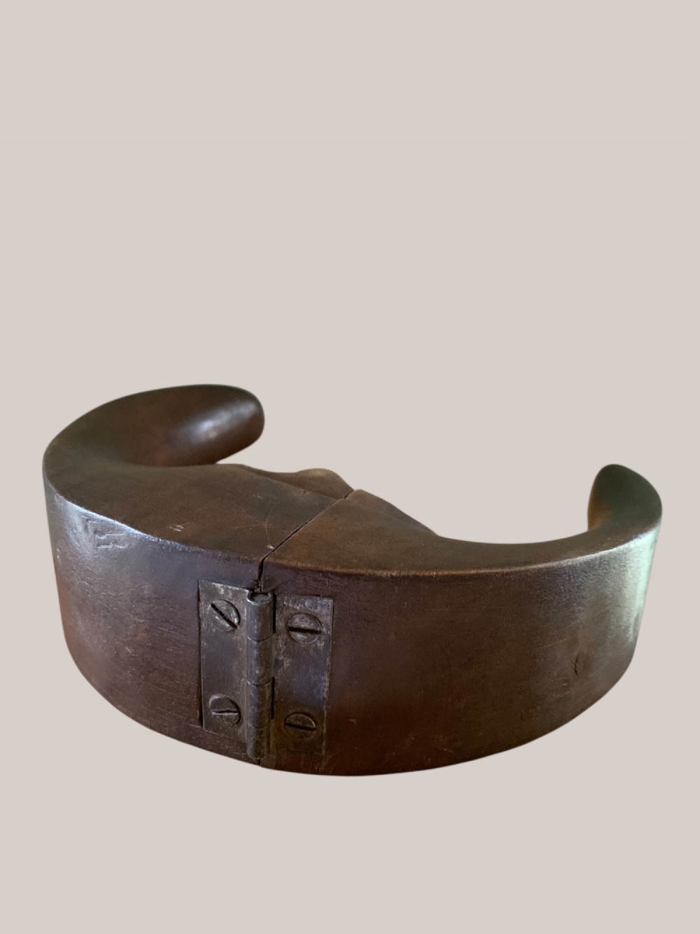 A dark brown carved wooden nutcracker shaped like a crescent moon with a human facial profile carved into the inner curve. View VI