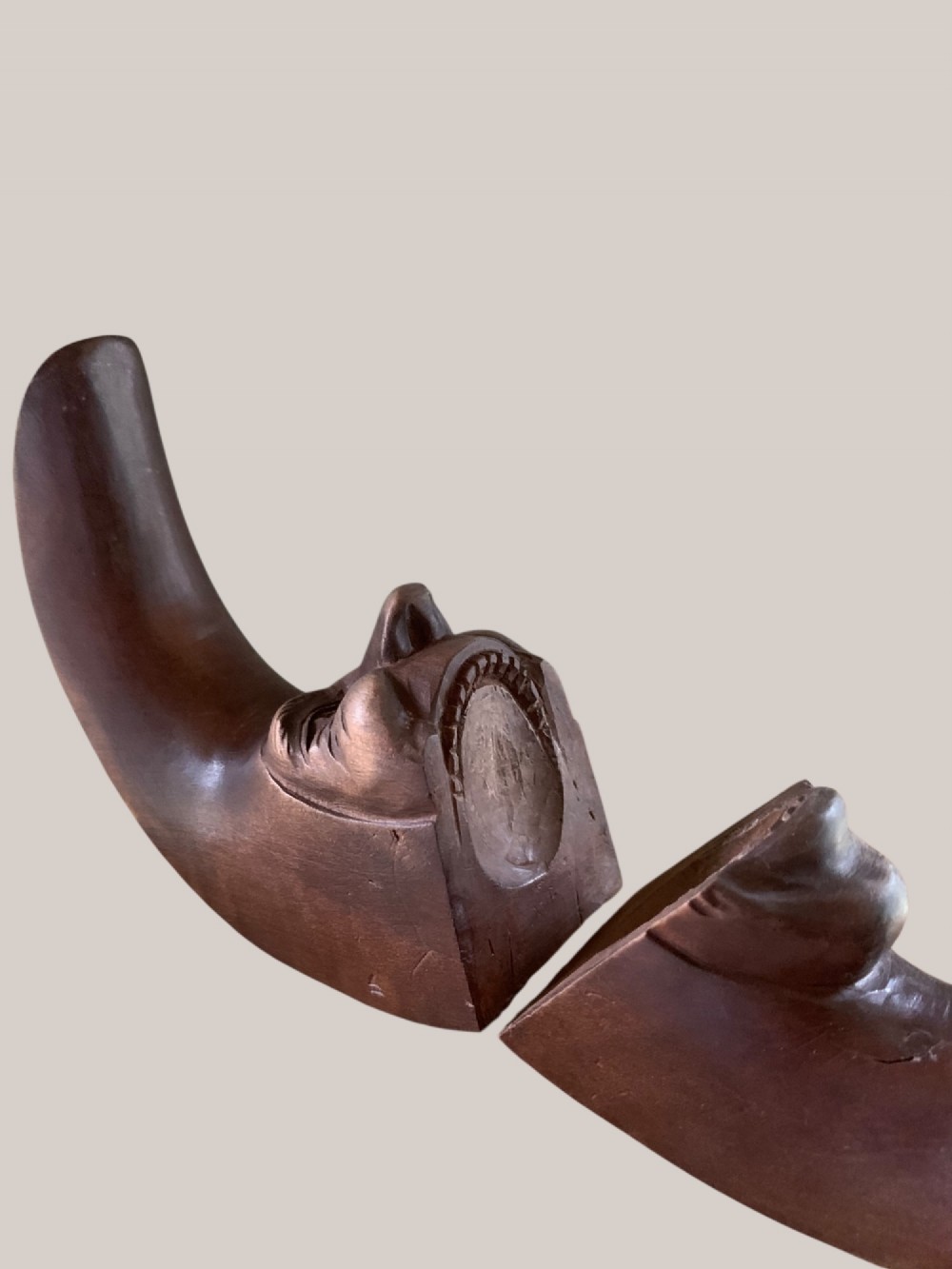 A dark brown carved wooden nutcracker shaped like a crescent moon with a human facial profile carved into the inner curve. View VIII