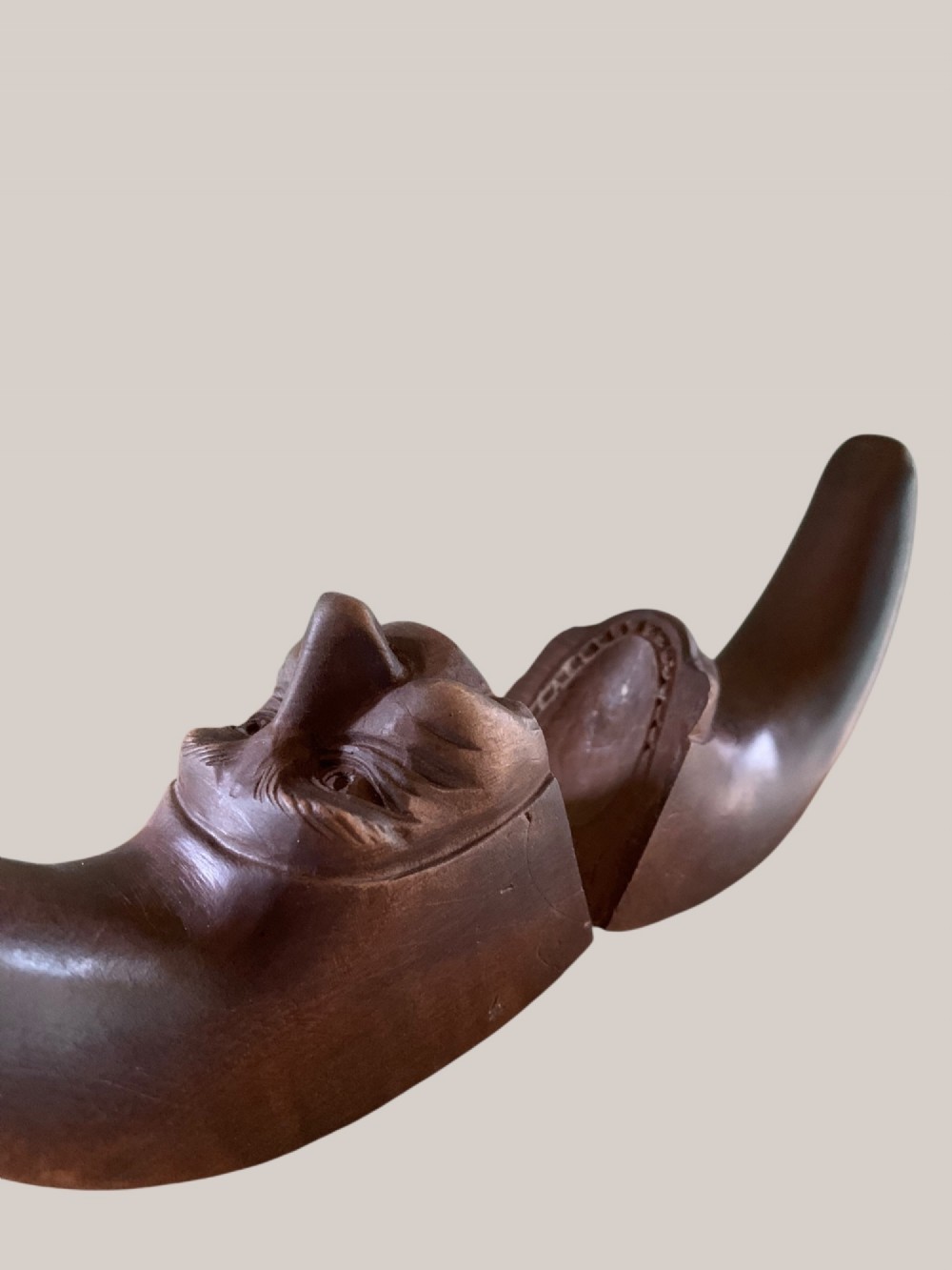 A dark brown carved wooden nutcracker shaped like a crescent moon with a human facial profile carved into the inner curve. View IX