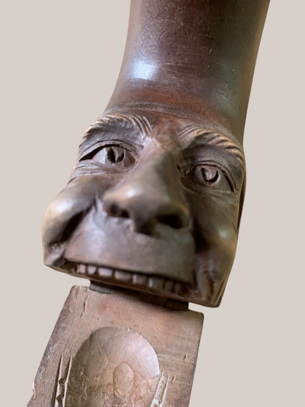 A dark brown carved wooden nutcracker shaped like a crescent moon with a human facial profile carved into the inner curve. View XI