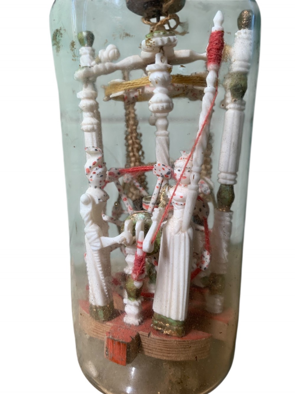 A clear glass bottle housing a detailed hand-carved bone miniature structure inside, topped with a cork and a dark carved bust finial stopper. View VIII