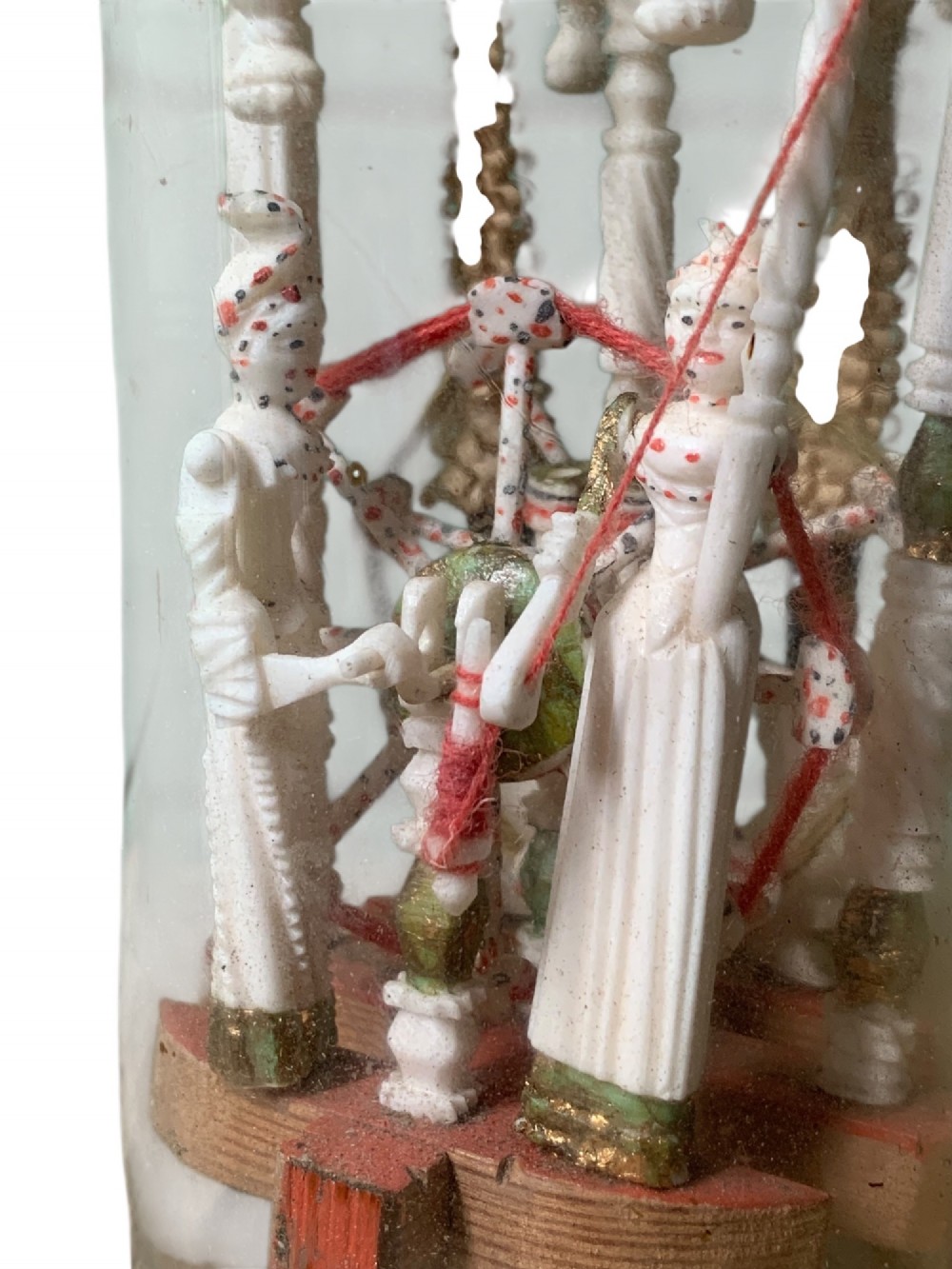 A clear glass bottle housing a detailed hand-carved bone miniature structure inside, topped with a cork and a dark carved bust finial stopper. View XII