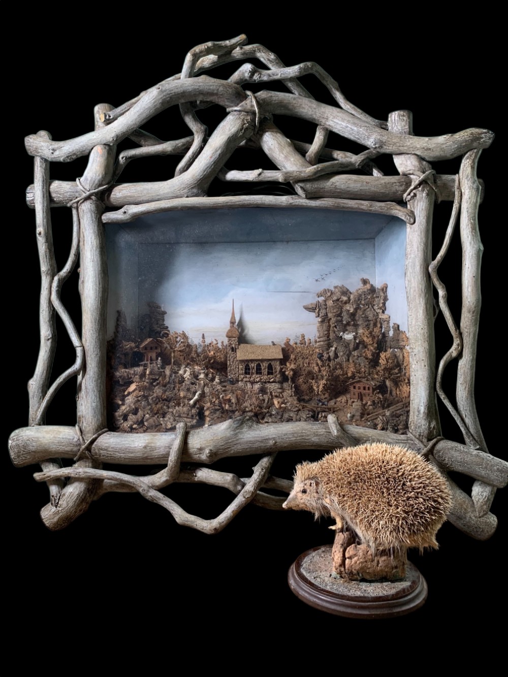An antique three-dimensional cork diorama depicting a village church scene enclosed within a frame crafted from intertwined rustic twigs. View II