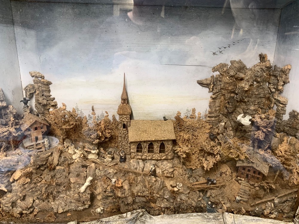 An antique three-dimensional cork diorama depicting a village church scene enclosed within a frame crafted from intertwined rustic twigs. View VII