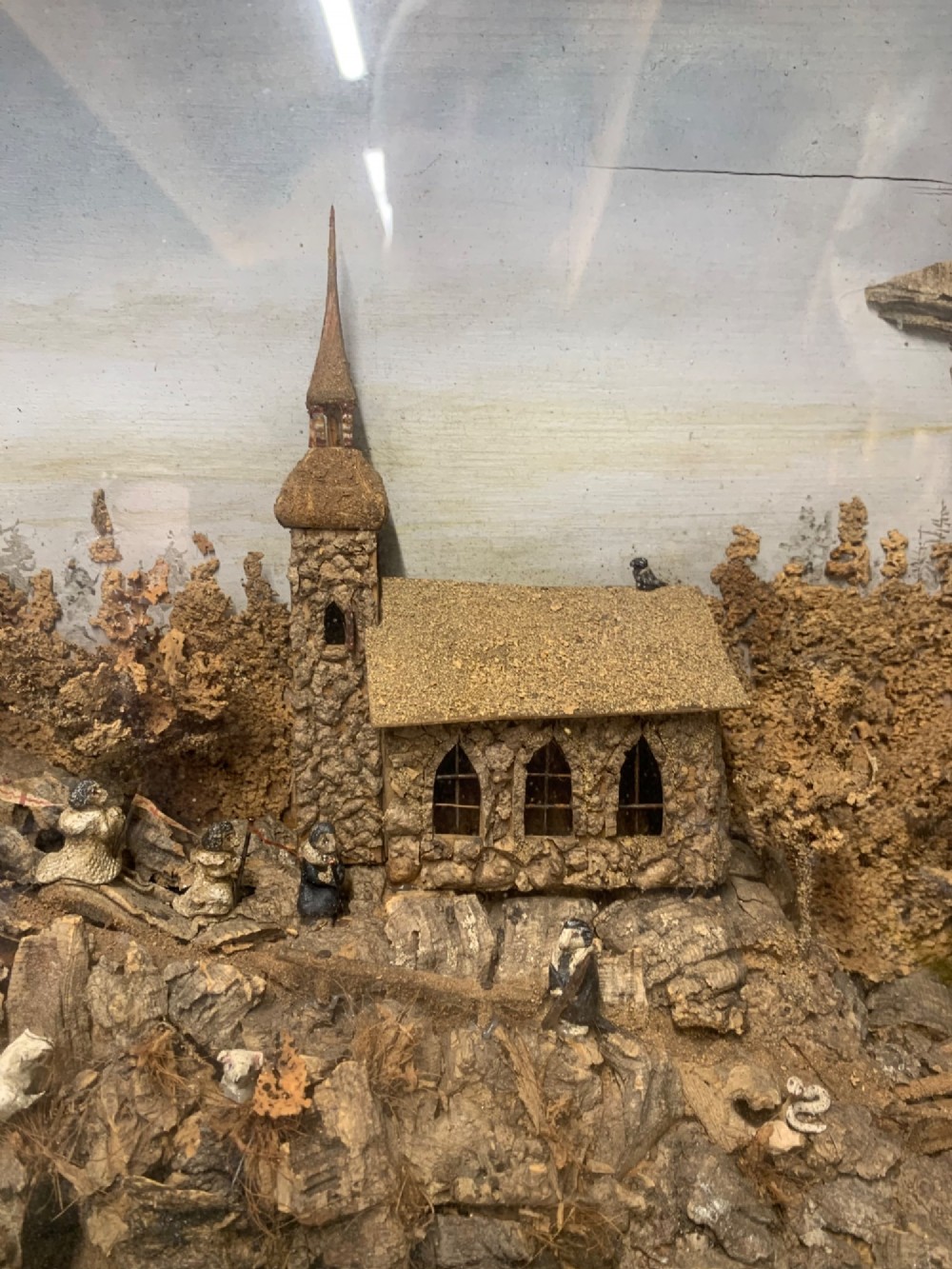 An antique three-dimensional cork diorama depicting a village church scene enclosed within a frame crafted from intertwined rustic twigs. View IX