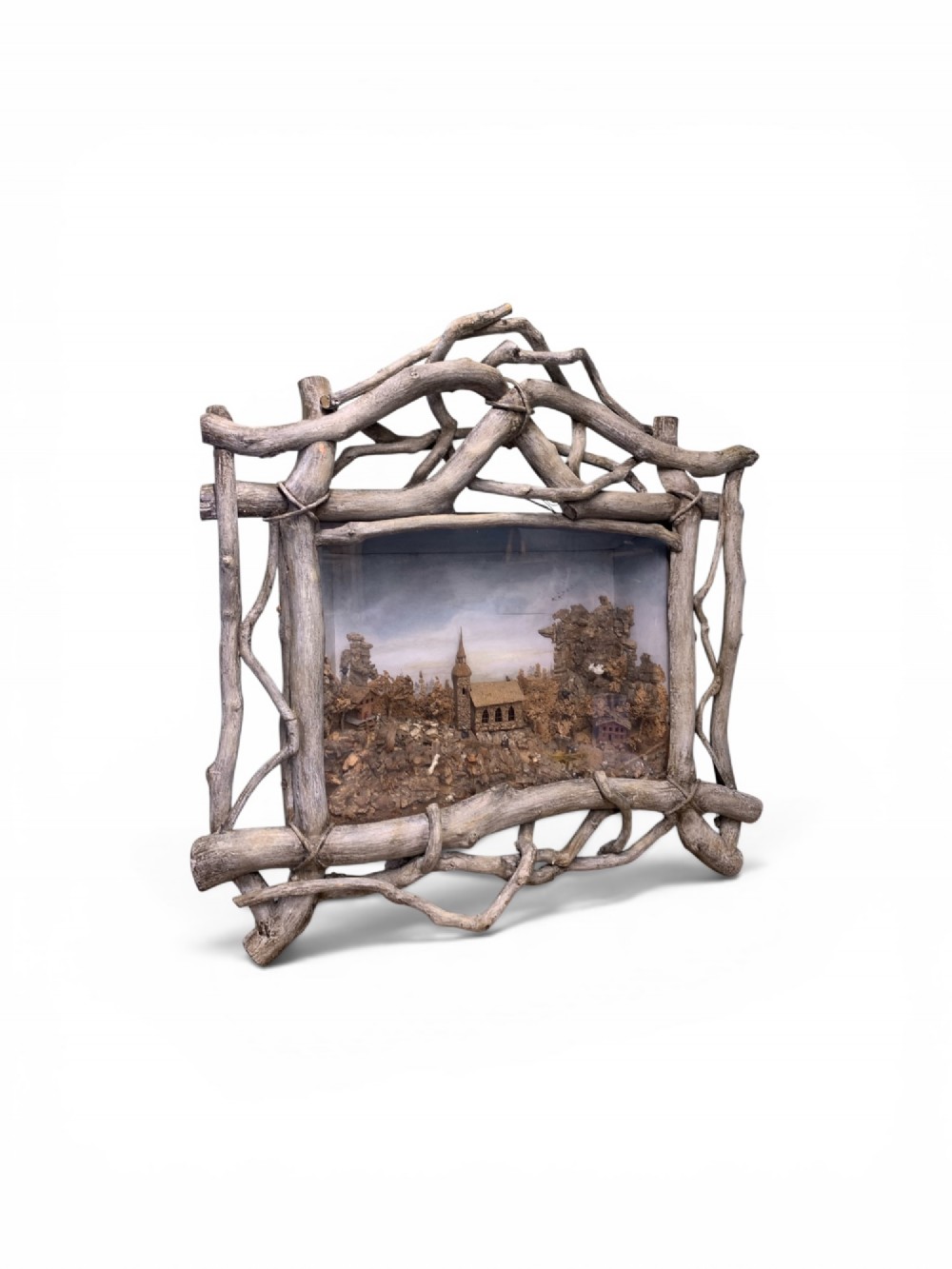 An antique three-dimensional cork diorama depicting a village church scene enclosed within a frame crafted from intertwined rustic twigs. View X