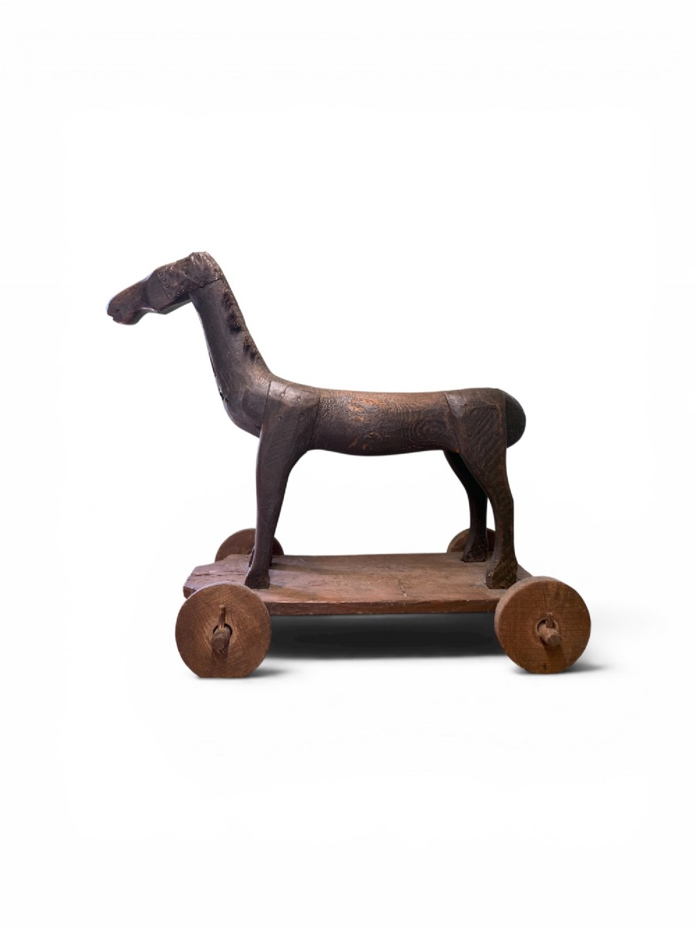 A naive hand-carved dark wood figure of a horse mounted on a flat wooden base with four simple circular wheels.