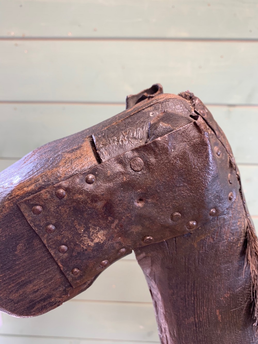 A naive hand-carved dark wood figure of a horse mounted on a flat wooden base with four simple circular wheels. View III