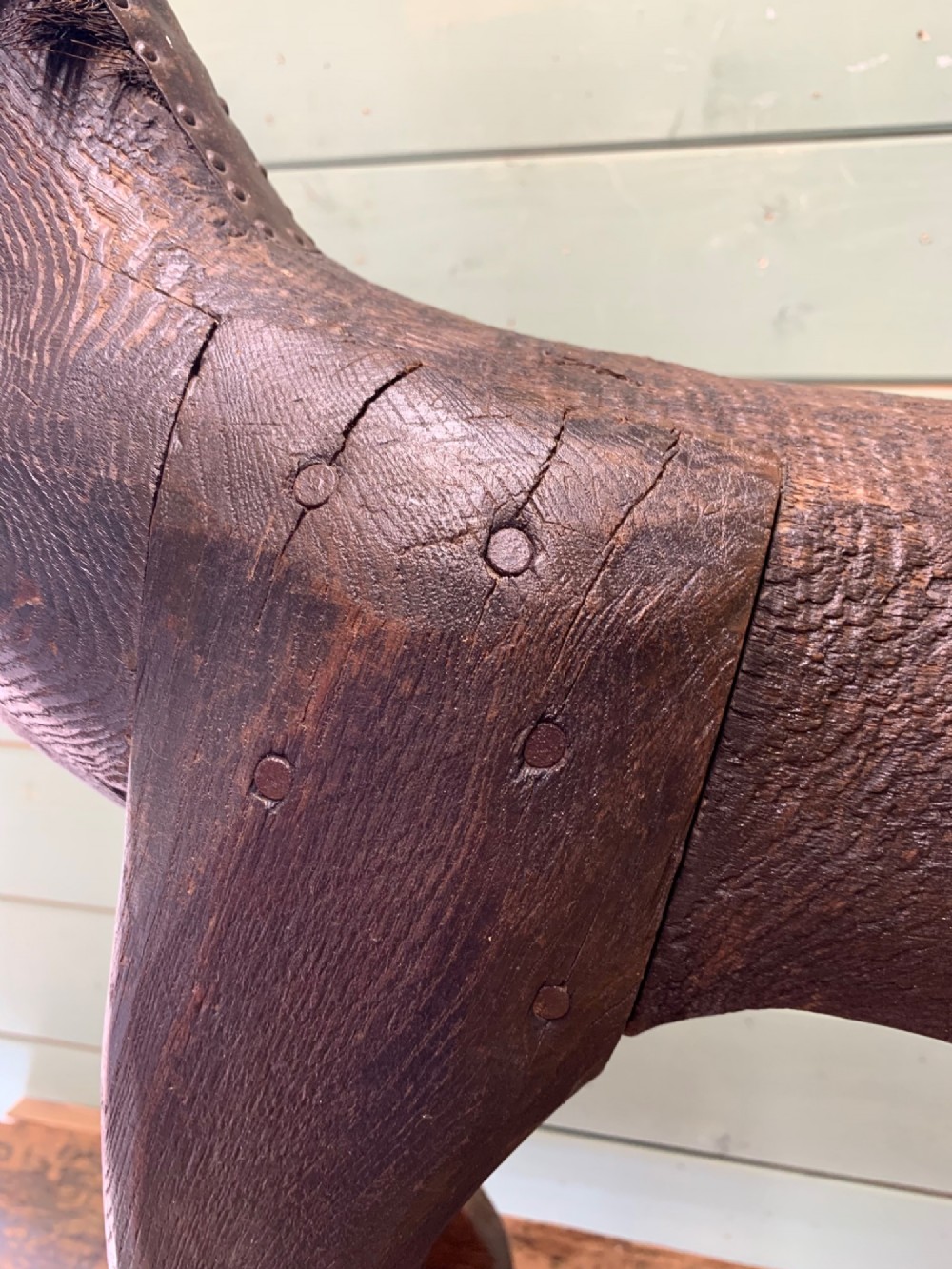 A naive hand-carved dark wood figure of a horse mounted on a flat wooden base with four simple circular wheels. View VII