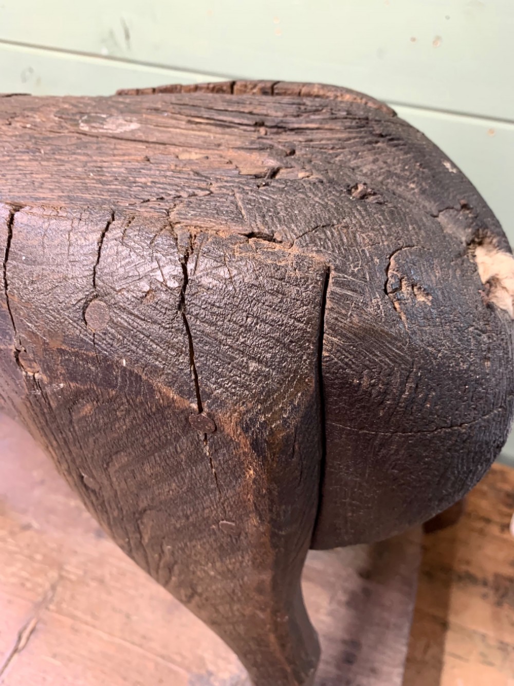 A naive hand-carved dark wood figure of a horse mounted on a flat wooden base with four simple circular wheels. View IX