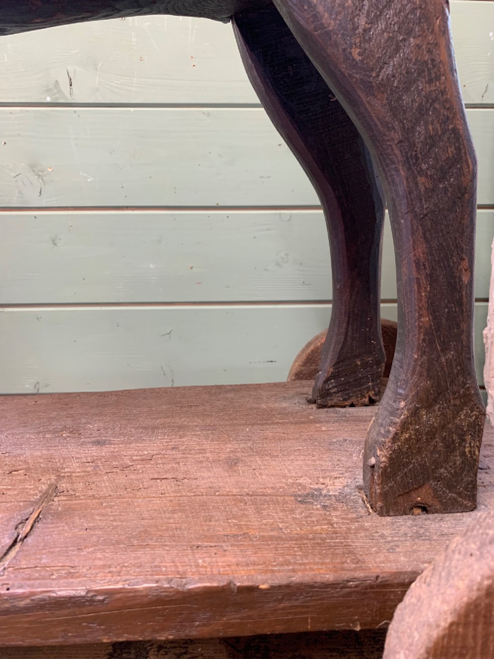 A naive hand-carved dark wood figure of a horse mounted on a flat wooden base with four simple circular wheels. View XI