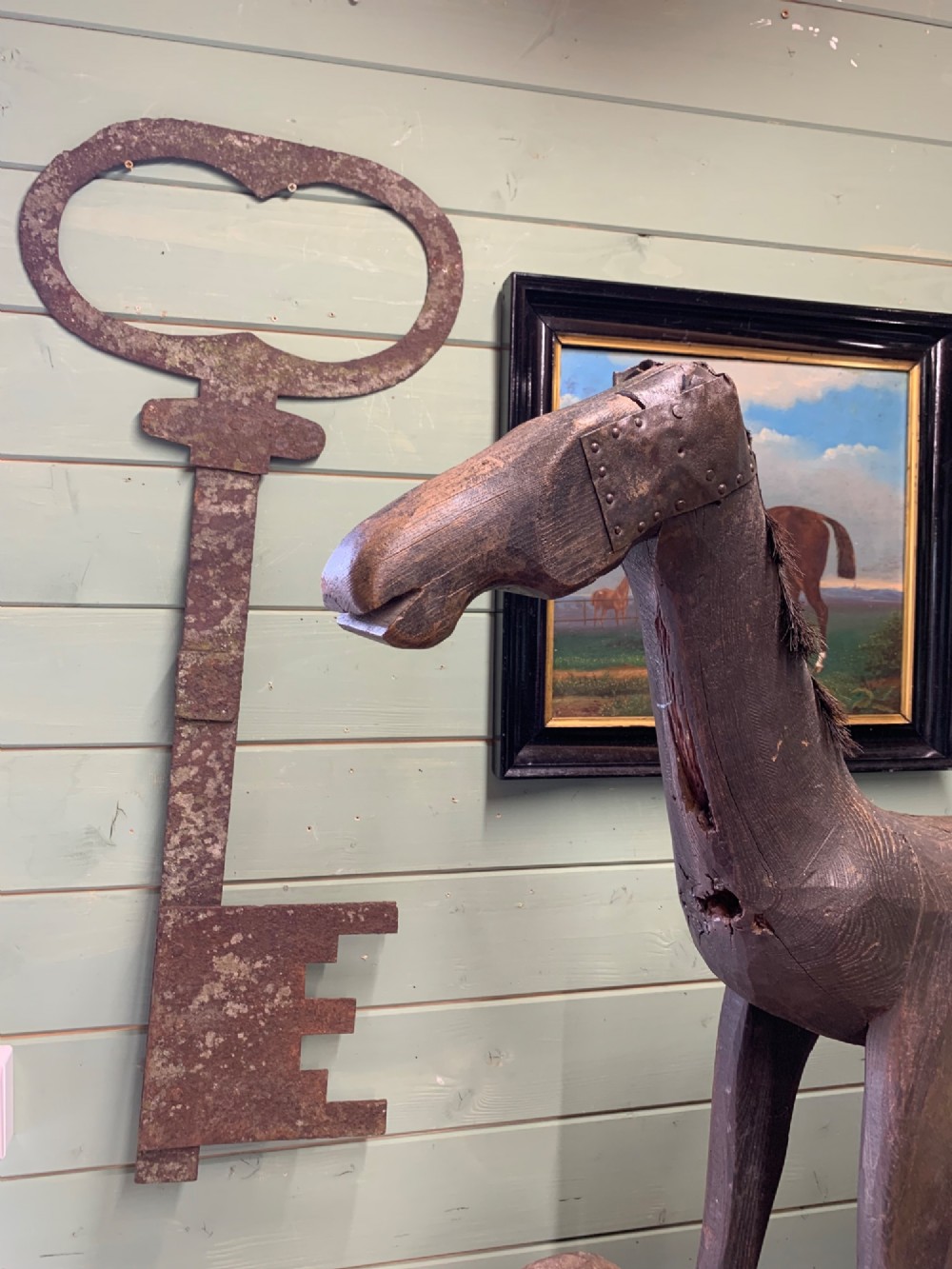 A naive hand-carved dark wood figure of a horse mounted on a flat wooden base with four simple circular wheels. View XIV