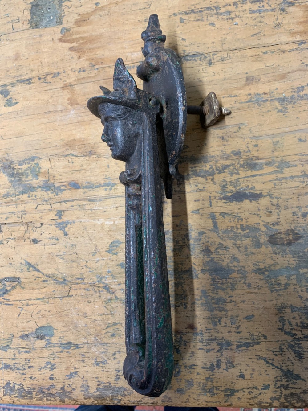 A Victorian cast iron door knocker featuring a sculpted classical Hermes head atop a drop-down loop striker. View V