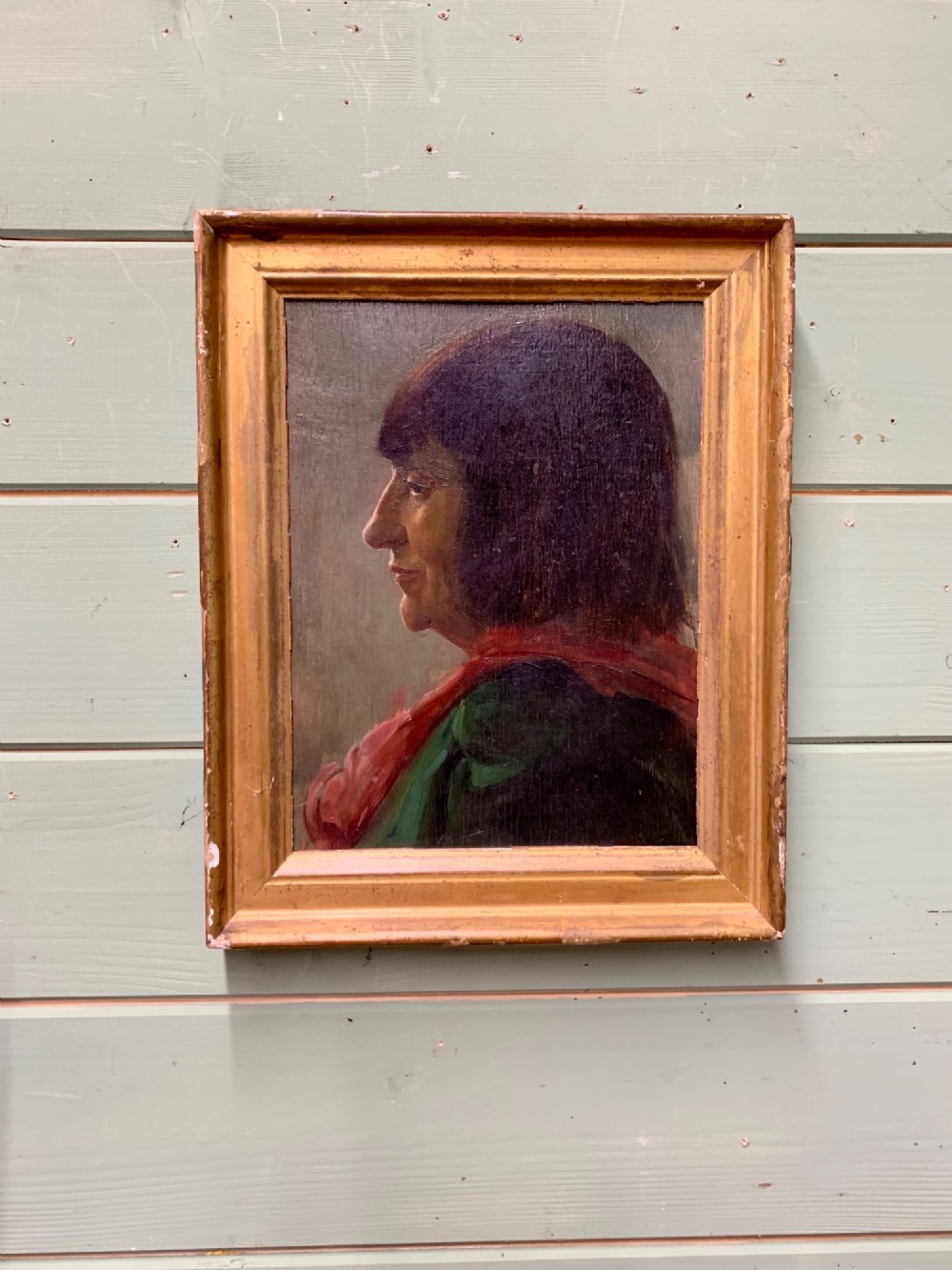 A side profile oil portrait painting of a woman with dark bobbed hair wearing a red scarf against a muted grey background. View II