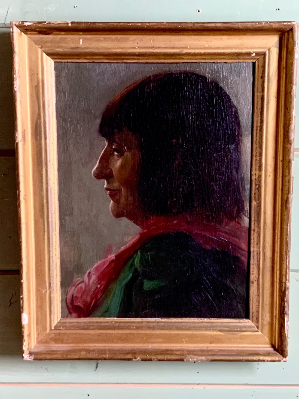 A side profile oil portrait painting of a woman with dark bobbed hair wearing a red scarf against a muted grey background. View III