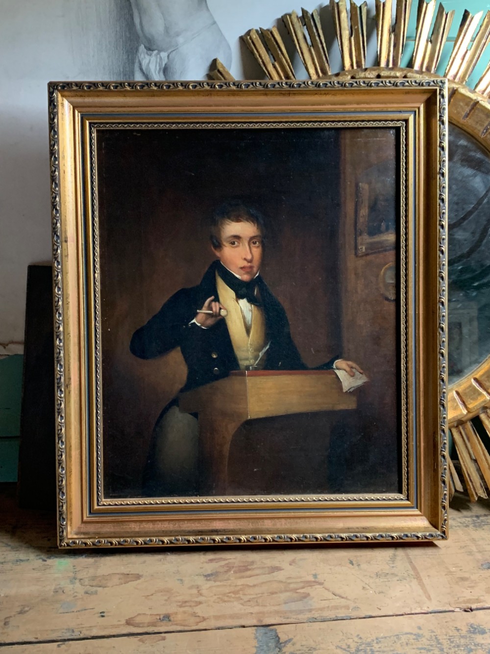 An early 19th-century oil portrait depicting a gentleman at a podium holding a small mallet, housed within a gold leaf frame.