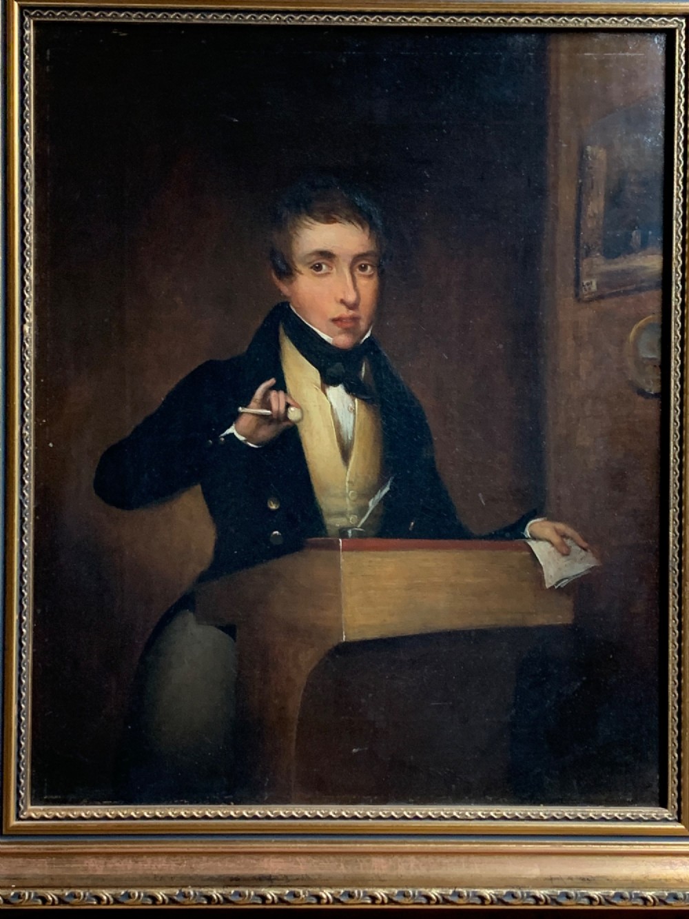 An early 19th-century oil portrait depicting a gentleman at a podium holding a small mallet, housed within a gold leaf frame. View III