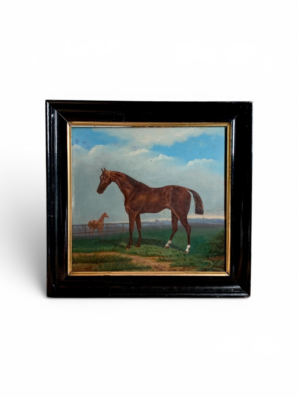 An antique oil painting on wood panel depicting a brown horse standing in a grassy landscape under a blue sky, set within a black ebonised frame with a gilt inner border.