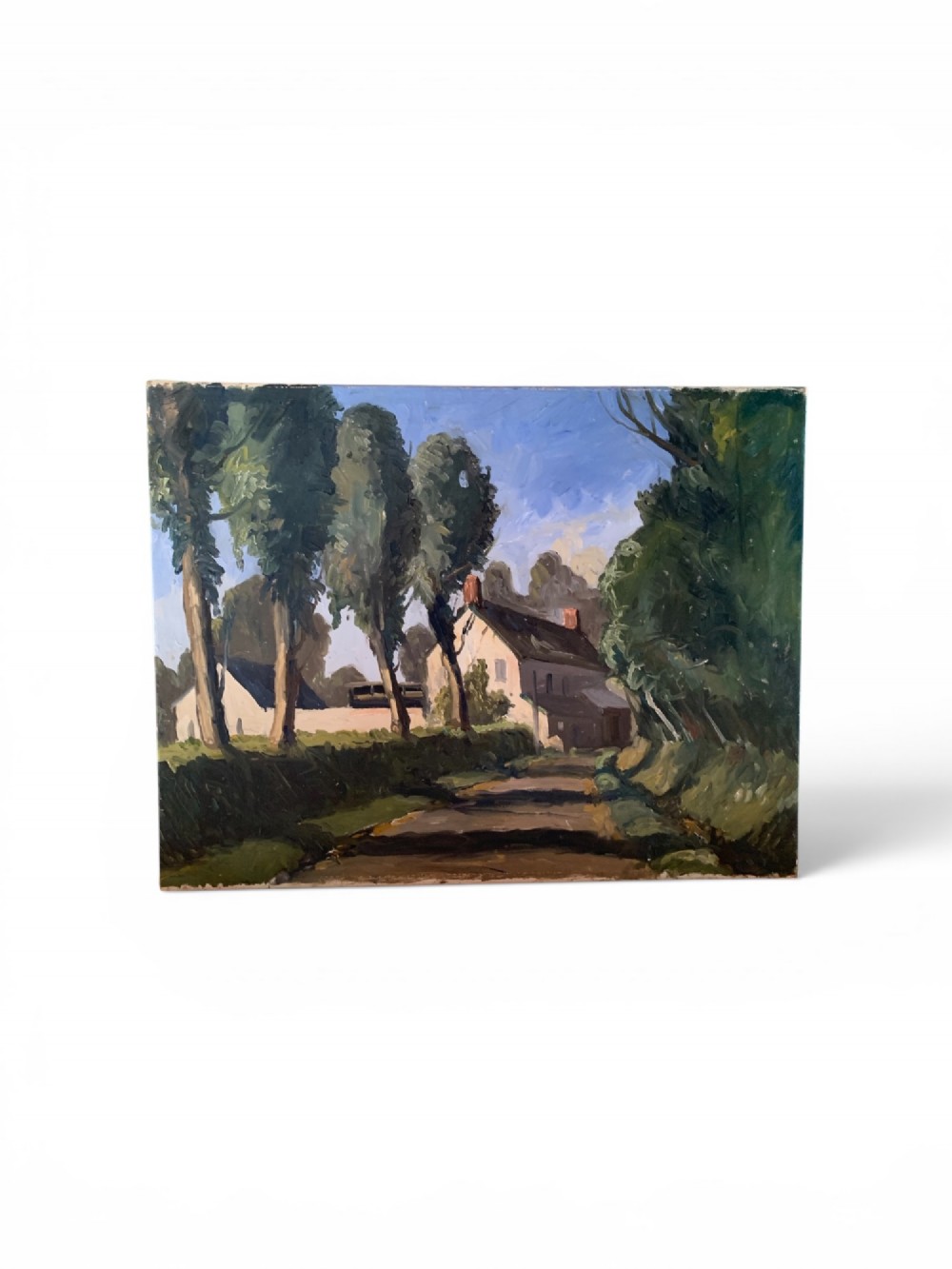 An early twentieth-century French oil painting depicting a sunlit country lane leading past tall trees towards a white farmhouse with terracotta chimneys under a light blue sky. View II