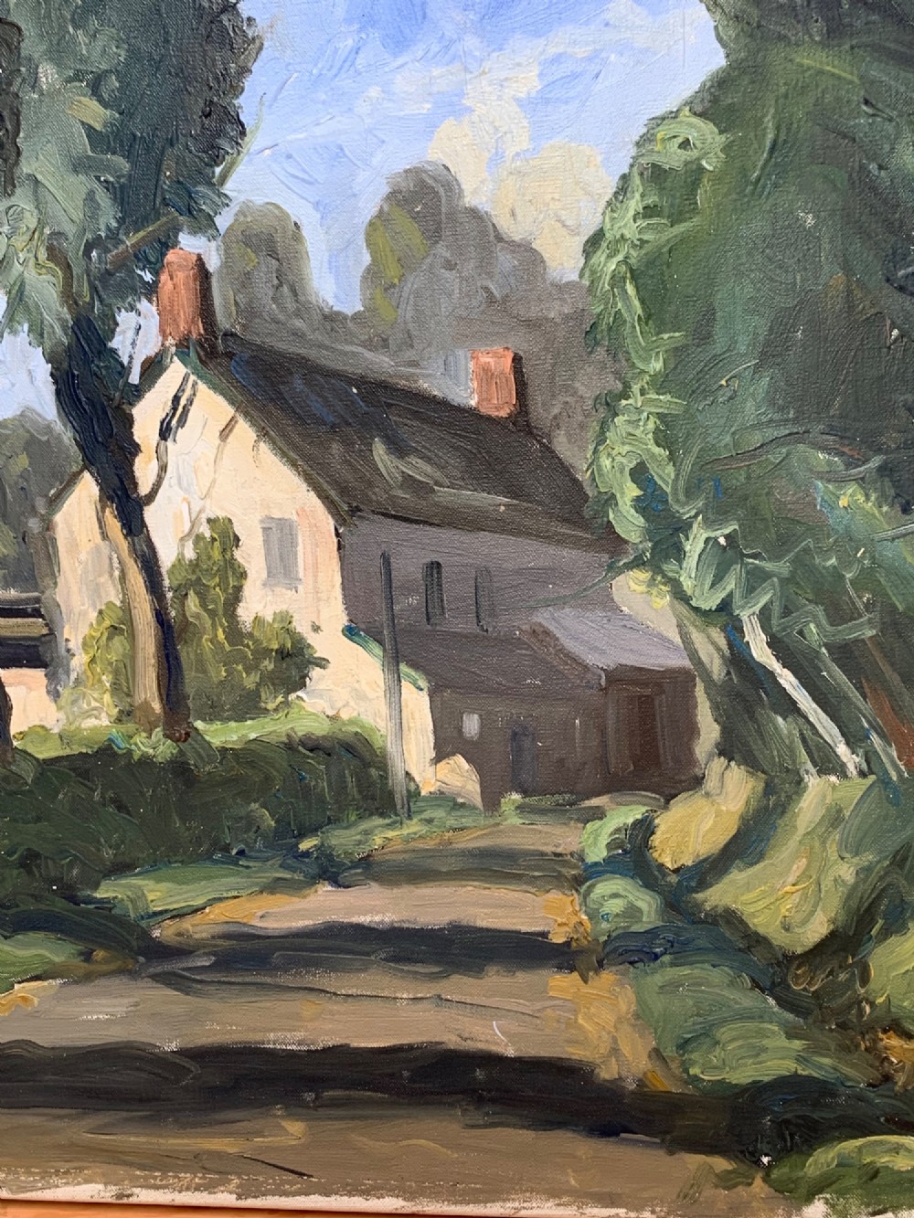 An early twentieth-century French oil painting depicting a sunlit country lane leading past tall trees towards a white farmhouse with terracotta chimneys under a light blue sky. View IV