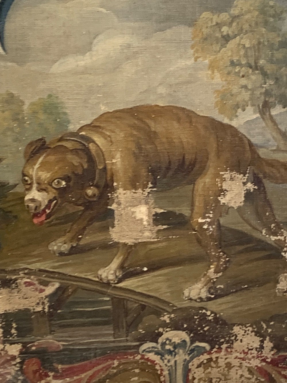 An early 19th-century oil painting on canvas featuring a brown dog framed by a floral cartouche against a muted sage green background. View V