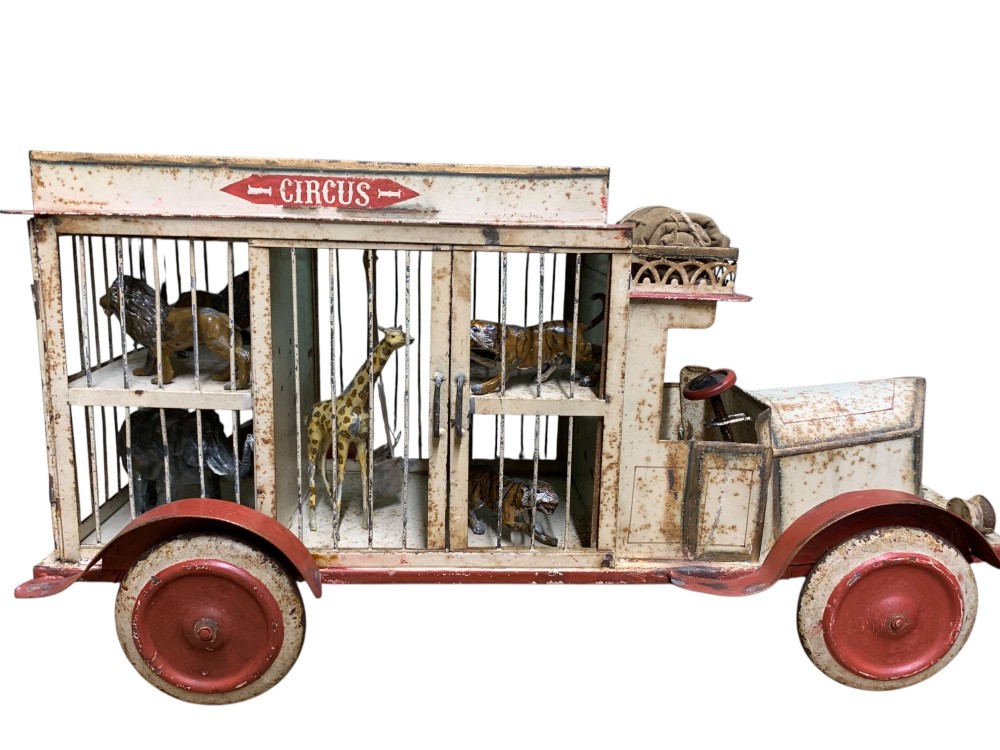 A 1920s painted tinplate Kibri circus lorry featuring cream side cage bars, red wheels, red accents, and miniature animal figures enclosed inside. View II