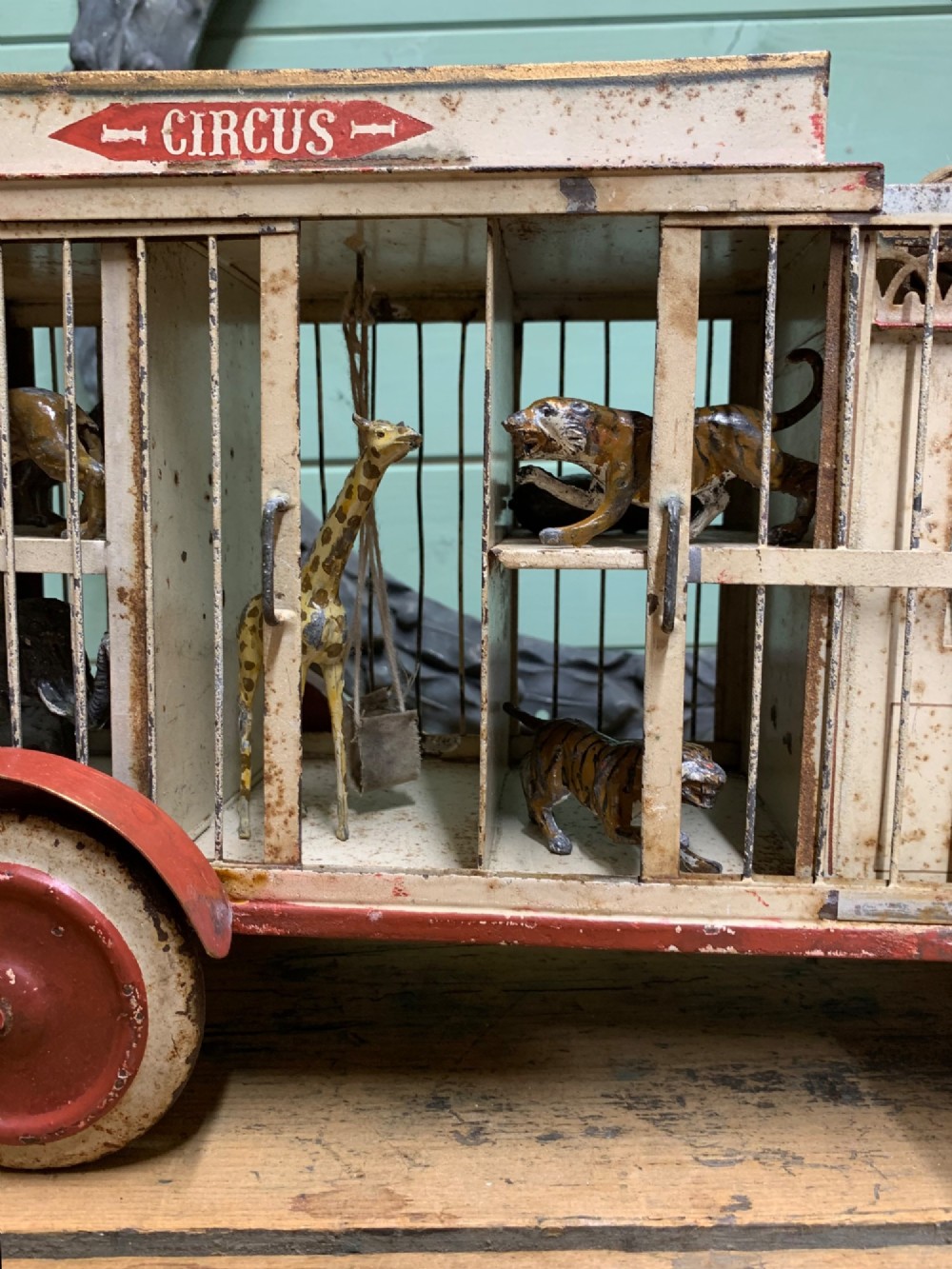 A 1920s painted tinplate Kibri circus lorry featuring cream side cage bars, red wheels, red accents, and miniature animal figures enclosed inside. View IV