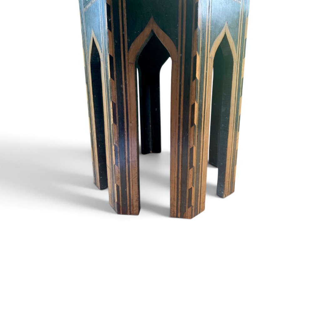 An early 20th-century octagonal Moorish side table made of dark wood with geometric mother-of-pearl inlay and pointed arch legs. View V
