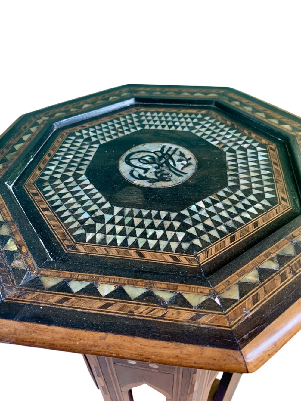 An early 20th-century octagonal Moorish side table made of dark wood with geometric mother-of-pearl inlay and pointed arch legs. View VII