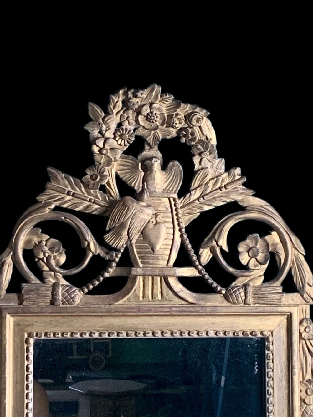 An 18th-century French giltwood marriage mirror with an ornate carved crest featuring doves, floral garlands, and a rectangular beaded mirror frame. View V