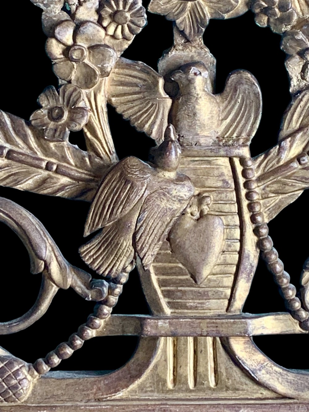 An 18th-century French giltwood marriage mirror with an ornate carved crest featuring doves, floral garlands, and a rectangular beaded mirror frame. View VI