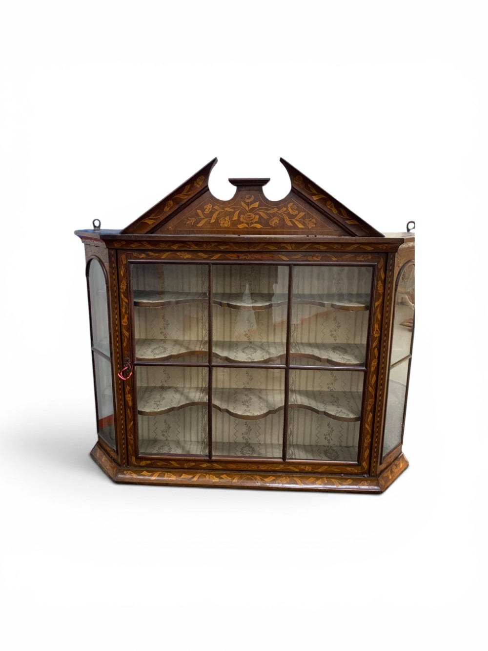 An 18th-century Dutch wall cabinet made of warm brown wood with botanical marquetry inlays, featuring a central glazed door, canted side panels, and a shaped pediment. View III