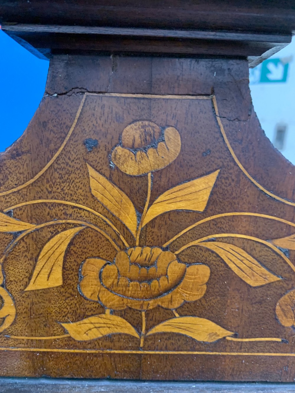 An 18th-century Dutch wall cabinet made of warm brown wood with botanical marquetry inlays, featuring a central glazed door, canted side panels, and a shaped pediment. View IV