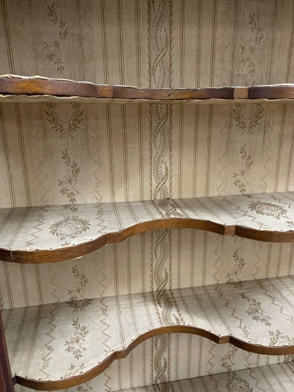 An 18th-century Dutch wall cabinet made of warm brown wood with botanical marquetry inlays, featuring a central glazed door, canted side panels, and a shaped pediment. View VI