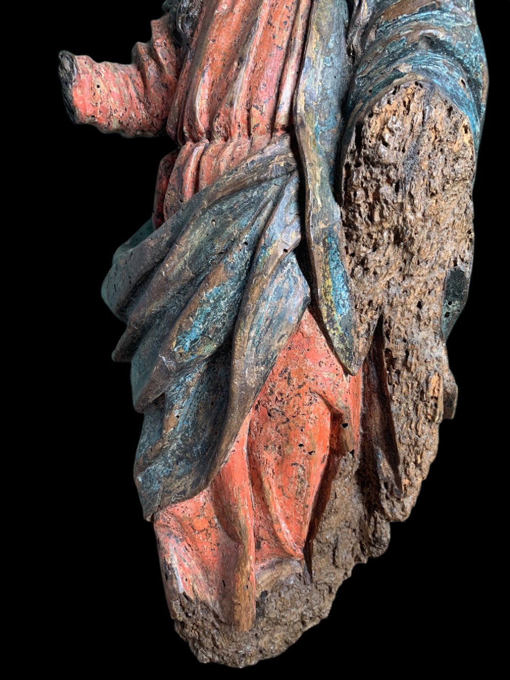 An eighteenth-century carved wood figure of a saint featuring red and blue polychrome paint, set upon a rectangular wooden base. View IV