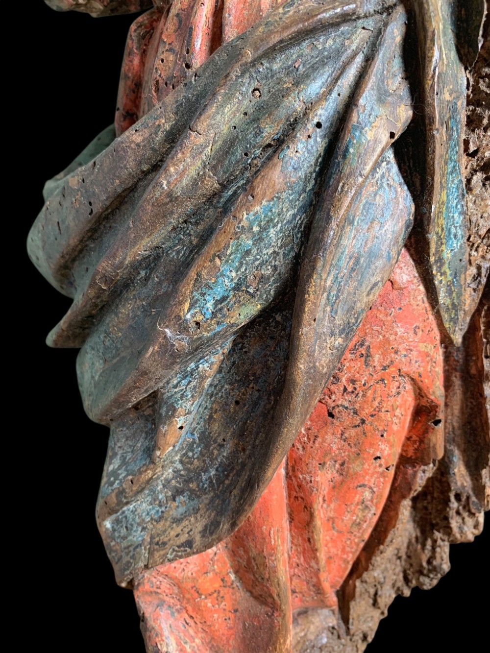 An eighteenth-century carved wood figure of a saint featuring red and blue polychrome paint, set upon a rectangular wooden base. View V