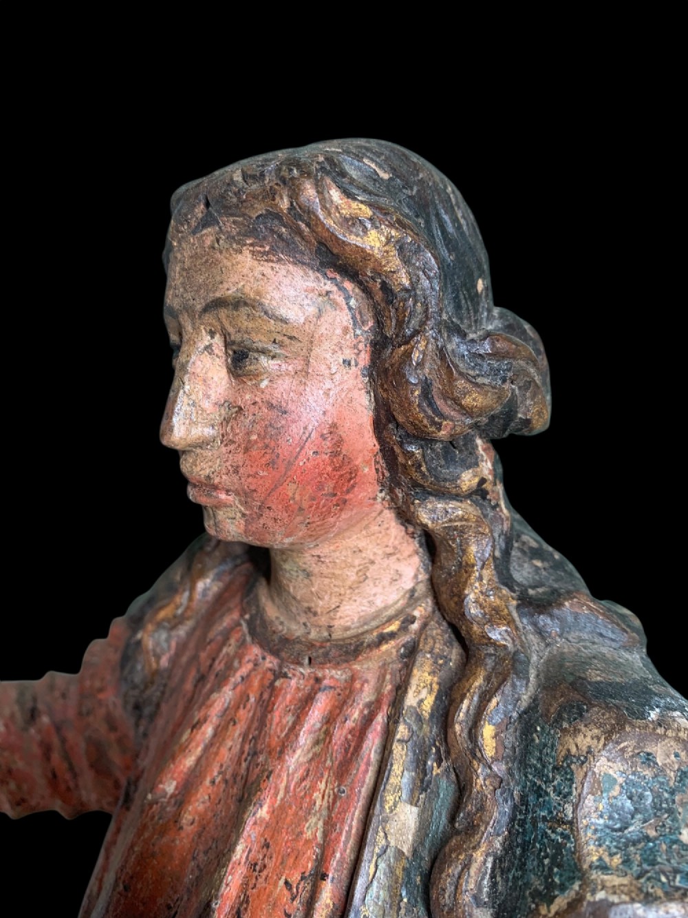 An eighteenth-century carved wood figure of a saint featuring red and blue polychrome paint, set upon a rectangular wooden base. View VI