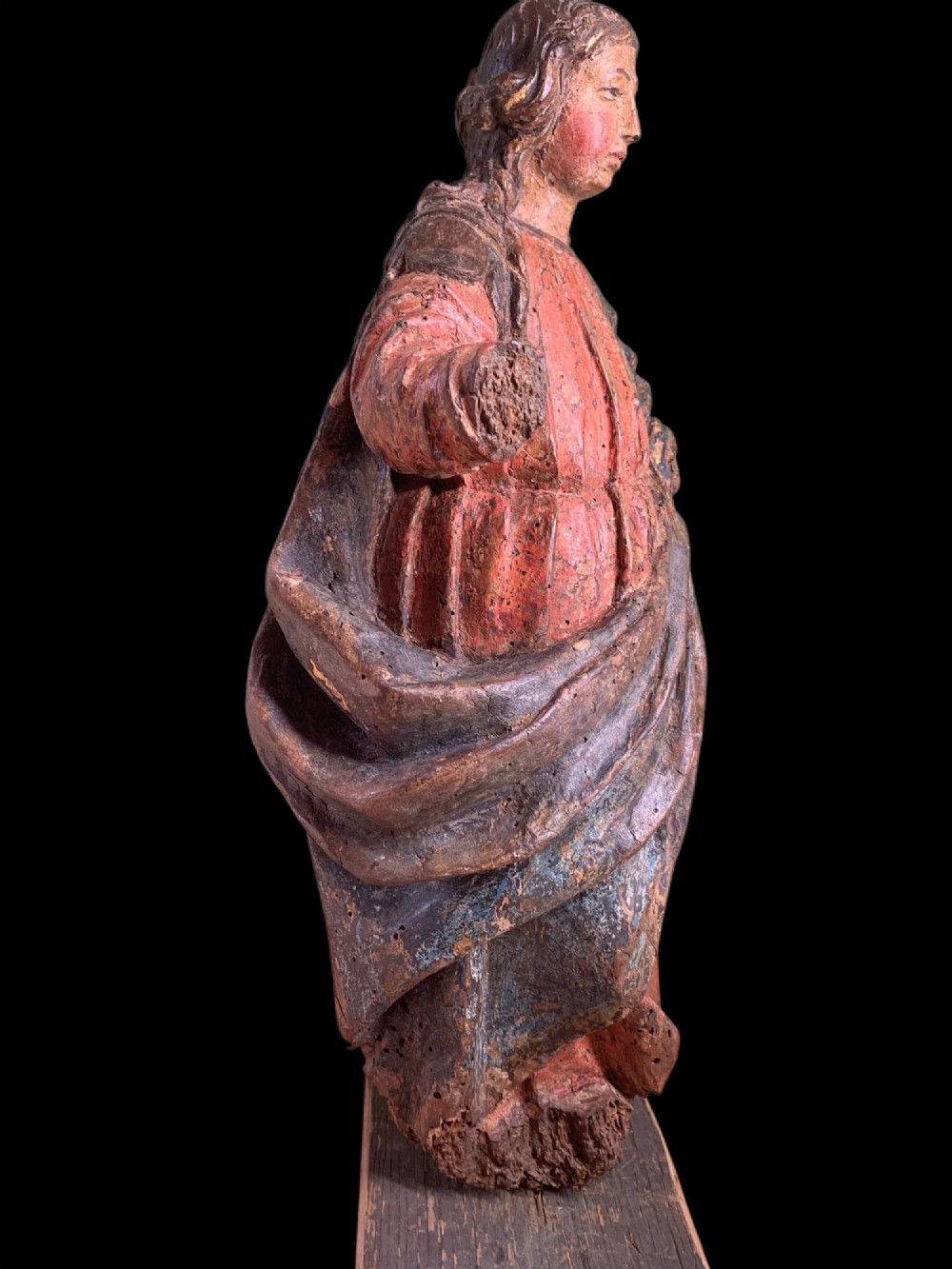 An eighteenth-century carved wood figure of a saint featuring red and blue polychrome paint, set upon a rectangular wooden base. View VIII